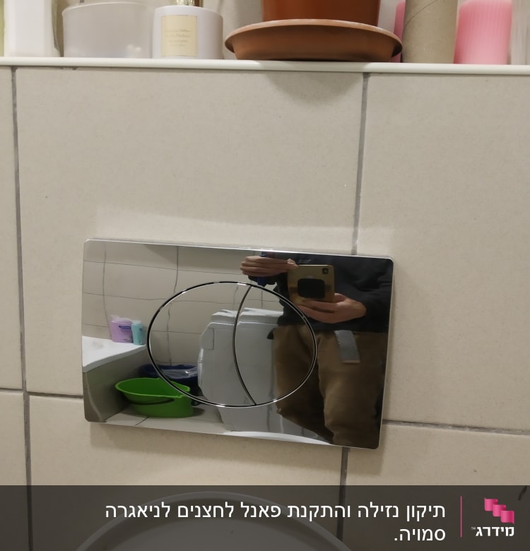 לחצן הדחה כסוף על קיר חדר אמבטיה